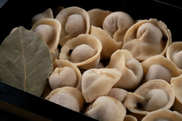 Russian Pelmeni fresh Dumplings with Meat in box on dark background
