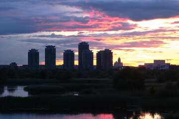 Naklejka premium Bucharest city skyline seen from Vacaresti Park Nature Reserve at sunset, with skyscraper towers and landmarks Palace of Parliament and People's Salvation Cathedral to the right.