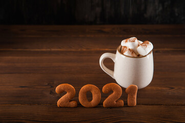 Concept with marshmallows in a mug and gingerbread cookie on a dark background. Christmas, coffee, tea, mug, marshmallows, cozy. Happy new year 2021. Winter concept close-up and copy space on dark bac