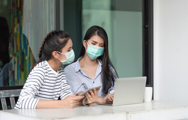 Two Asian young woman wearing medical mask to protect coronavirus or COVID-19 disease while working at the outside