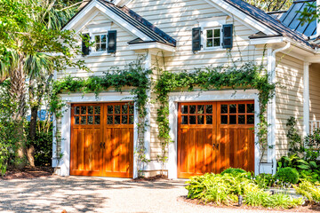 American residential house building in Charleston, South Carolina with two garage doors exterior with wooden architecture and ivy climbing plant - obrazy, fototapety, plakaty