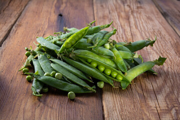 open pods of green peas on a wooden table close-up, harvest from the garden
