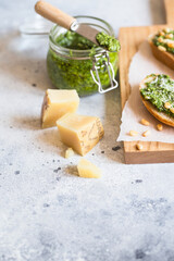 Toasts with traditional Italian basil pesto sauce on a light grey stone table. Green pesto with pine nuts and parmesan