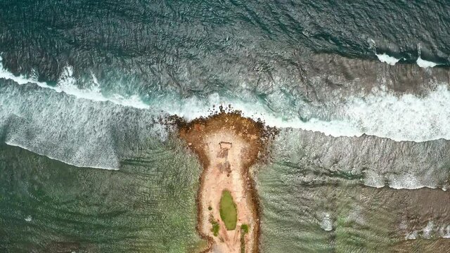 Aerial view of artificial structures for the safety of people. Breakwaters save from strong waves during tropical storms. Ocean waves beat into cracks in the rocks. Drone shot of sea waves crashing.