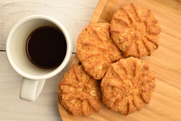 Fragrant tasty, sweet cereal cookies on a bamboo plate with a white cup, close-up, on a wooden table.