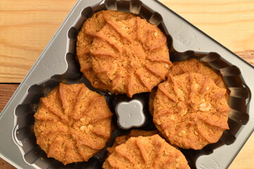 Fragrant tasty, sweet cereal cookies in a plastic container, close-up, on a wooden table.