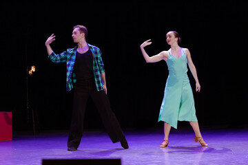 A pair of dancers a man and a woman perform in a theater on stage in a dance musical show.