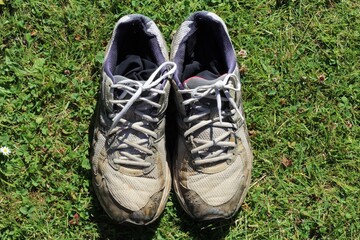 pair of dirty used trainers on grass in the garden on a sunny day