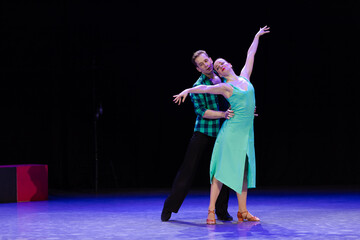 A pair of dancers a man and a woman perform in a theater on stage in a dance musical show.