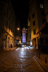 Fototapeta na wymiar Famous Galata Tower from street view cobblestone roads are illuminated with motorcycle except the galata tower is out of focus