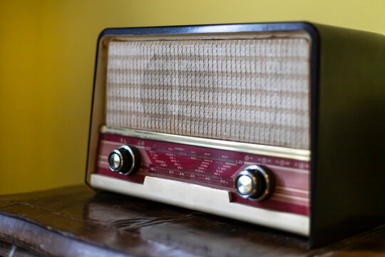 an old vintage radio standing on a wooden furniture