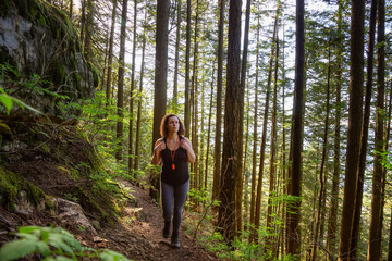 Adventurous Girl Hiking in a Green and Vibrant Rain Forest during a sunny spring day. Taken in Abbotsford, East of Vancouver, British Columbia, Canada. Nature Background Panorama