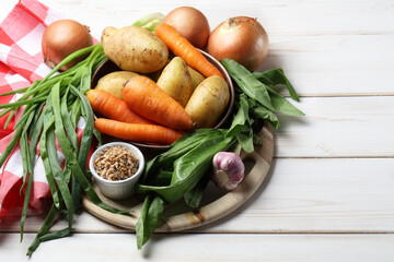 Raw potatoes, carrots, onions, garlic, sorrel and sprouted wheat on the table