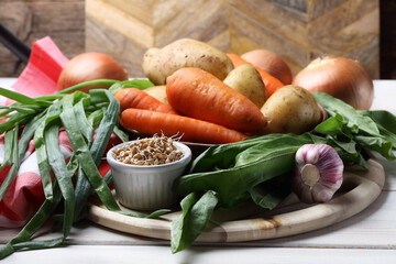 Raw potatoes, carrots, onions, garlic, sorrel and sprouted wheat on the table