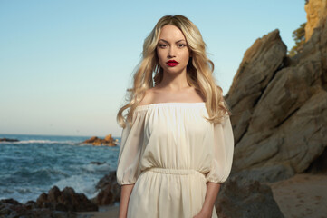 Fototapeta na wymiar Beautiful blonde woman on the beach. Lady in white dress