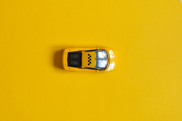 Toy car taxi on a yellow background with a top view.
