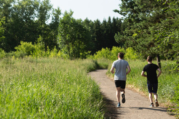 Two men running around doing sports in the park outdoors in the fresh air. Workout outdoors. Healthy lifestyle concept.