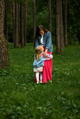 Fototapeta premium happy child girl hugs her mom standing on the grass in the park