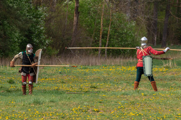 Knights in armor fight on the battlefield. Reconstruction of an ancient battle of the 15th century.