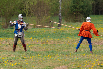 Knights in armor fight on the battlefield. Reconstruction of an ancient battle of the 15th century.