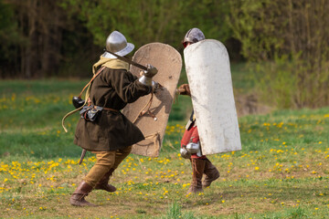 Knights in armor fight on the battlefield. Reconstruction of an ancient battle of the 15th century.