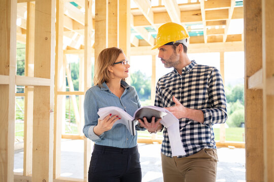 Female investor meeting with architect or engineer on construction site of her new house looking at blueprints