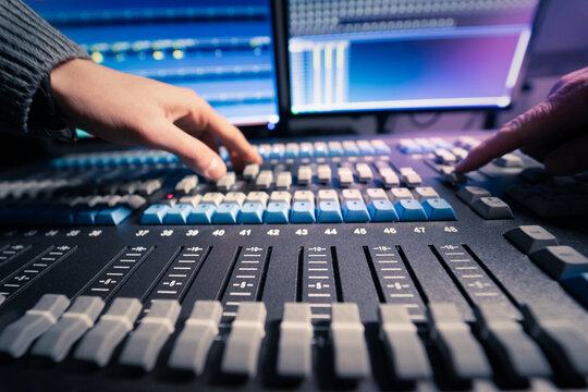 Mesa de control de iluminaci&oacute;n. Manos de cerca usando faders de mesa de iluminaci&oacute;n. Control de realizaci&oacute;n. Estudio de televisi&oacute;n. Producci&oacute;n de televisi&oacute;n.