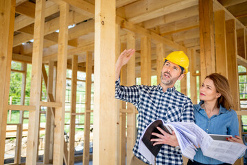 Female homeowner consults blueprints with architect or engineer on construction site of her new...