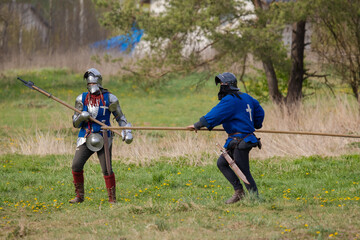 Knights in armor fight on the battlefield. Reconstruction of an ancient battle of the 15th century.