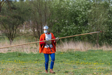 Knights in armor fight on the battlefield. Reconstruction of an ancient tournament of the 15th...