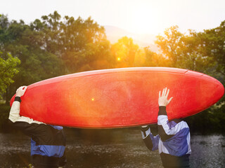 Two men carrying kayak outdoors