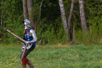Knights in armor fight on the battlefield. Reconstruction of an ancient tournament of the 15th...