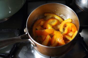 Candied peel of orange boiling in sugar syrup