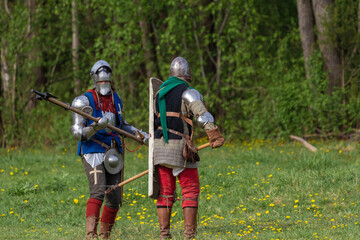 Knights in armor fight on the battlefield. Reconstruction of an ancient battle of the 15th century.