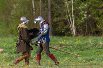 Knights in armor fight on the battlefield. Reconstruction of an ancient tournament of the 15th...