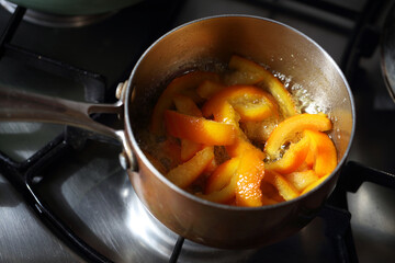 Candied peel of orange boiling in sugar syrup