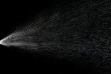 Liquid water spray mist from perfume bottle isolated on black. Aerosol splash background.