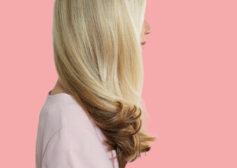 Senior woman with long blonde hair standing over pink background