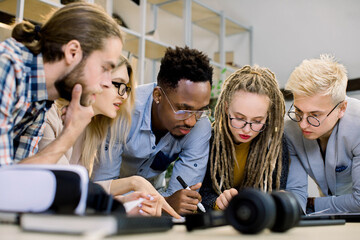Concentrated diverse multiethnic colleagues gather in office room to brainstorm and discuss financial statistics and joint project together. Office meeting, teamwork concept