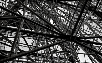 Looking up at numerous intersecting steel supports on an overcast day