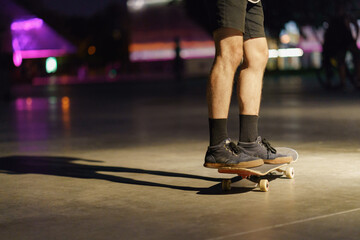 Fototapeta premium Photography of skateboarder's legs, shoes and skate in night park. Skateboarder getting ready to do the trick to jump. Sportive lifestyles of youth. Dangerous risk speed sports.