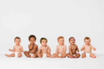 Blurred photo of Row of six multi ethnic Babies smiling in studio