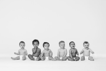 Black and white photo of Row of six multi ethnic Babies smiling in studio