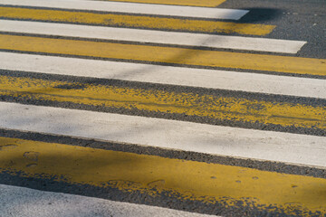 Fototapeta premium White and yellow stripes of the urban crosswalk at the Moscow street. Pedestrian crosswalk in the daytime. Concepts of the traffic safety rules.