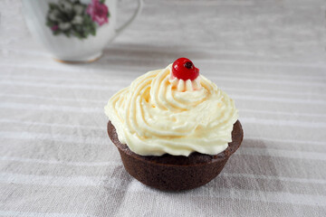 gluten free with rice and corn flour chocolate cake with cream cheese on a beige table with red currant berries and a Cup made at home