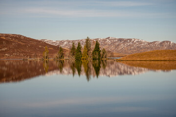tree reflections in Loch Tarff with a hint of snow and late autumn colour