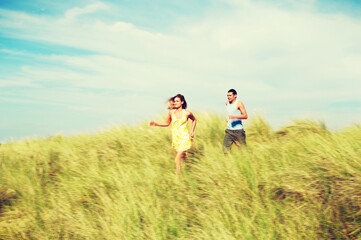 Fototapeta na wymiar Couple Running through Meadow