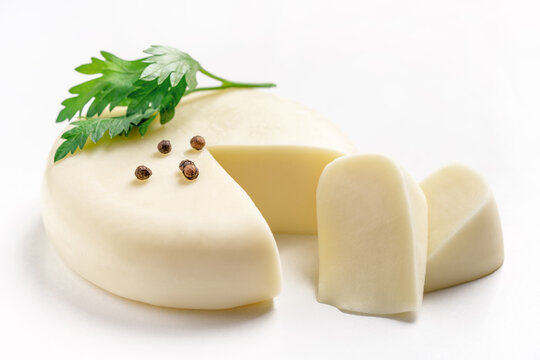 Soft Suluguni cheese wheel and pieces of Sulguni on white background. Traditional Georgian food