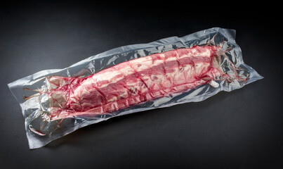 Raw veal spare loin ribs St Louis cut offered as closeup vacuum packed in plastic packaging on a...