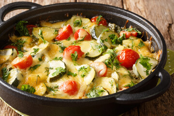Zucchini summer casserole with cheese and cherry tomatoes close-up in a pan on the table. horizontal